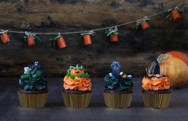 Símbolos de Halloween, preparación para las vacaciones. Cupcakes de calabaza naranja y decoración de madera