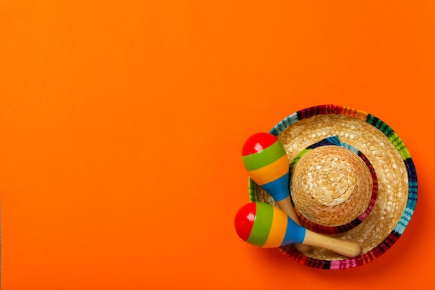 Símbolos mexicanos de maracas e sombrero em um fundo colorido