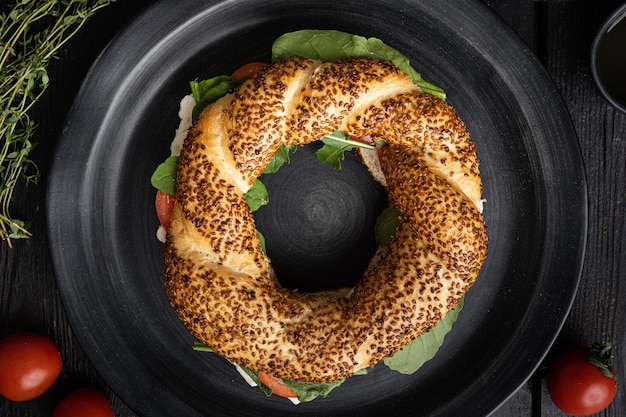 Simit-Bagelsandwich mit Kopfsalattomatenkäse auf Draufsicht des schwarzen Holztischhintergrundes flache Lage