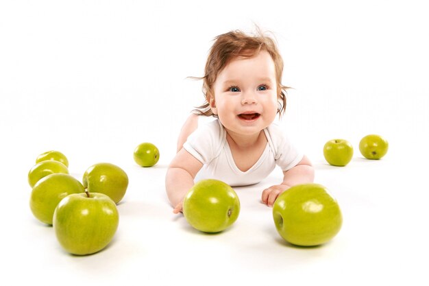 Simpático bebé rodeado de manzanas verdes