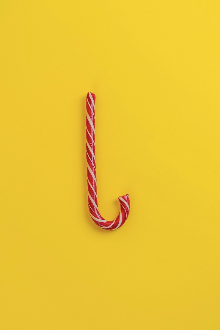 Foto un simple caramelo de navidad plano yacía aislado contra la superficie colorida, símbolo de las vacaciones de invierno