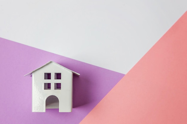 Simplemente diseñe con una casa de juguete blanca en miniatura aislada en blanco violeta rosa pastel colorido moda ge