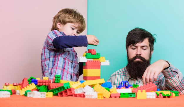 Simplesmente estar por perto construindo com o construtor colorido menino pequeno com o pai brincando juntos família feliz lazer amor desenvolvimento infantil pai e filho jogam jogo Família incomum melhor dia da família