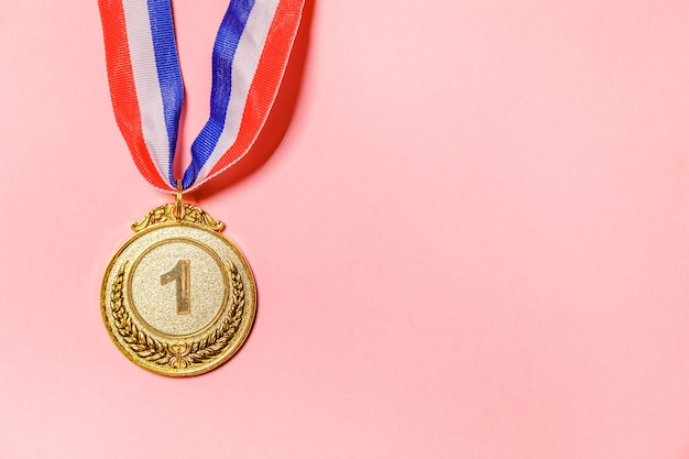 Foto simplesmente plana leigos vencedor do projeto ou medalha do troféu de ouro do campeão isolada no fundo colorido rosa. vitória em primeiro lugar de competição. conceito de vitória ou sucesso. espaço da cópia da vista superior.