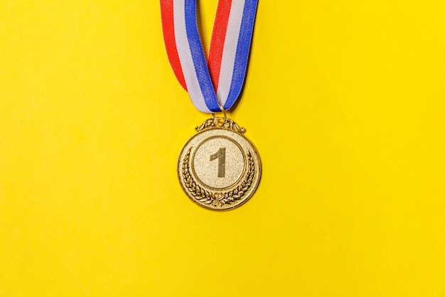 Foto simplesmente plana leigos vencedor ou medalha de troféu de campeão de ouro isolada em fundo colorido amarelo.