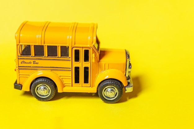 Simplesmente projete o ônibus escolar de carro de brinquedo clássico amarelo isolado em fundo colorido amarelo