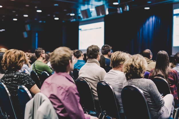 Simpósio de negócios e empreendedorismo Palestrante dando uma palestra na reunião de negócios Audiência na sala de conferências Vista traseira do participante não reconhecido na audiência