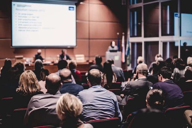 Simposio de negocios y emprendimiento El orador da una charla en una reunión de negocios Audiencia en la sala de conferencias Vista trasera de un participante no reconocido en la audiencia