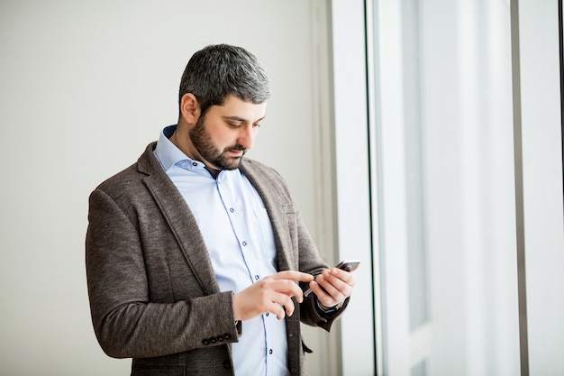 Simsendes Mobiltelefon des zufälligen städtischen Berufsgeschäftsmannes glücklich innerhalb des Büros