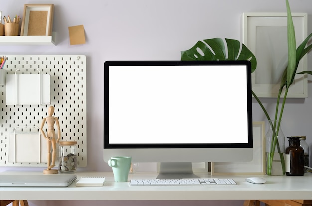 Simula la computadora en la tabla de espacio de trabajo loft que muestra una pantalla en blanco en blanco