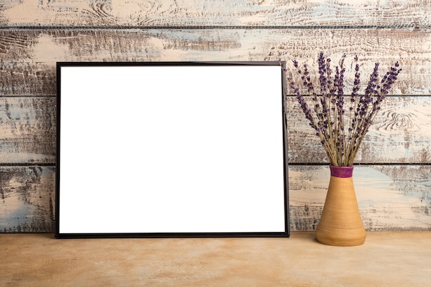 Simulacros de un cartel de marco vacío en una pared de tablas de madera. Manojo de lavanda en un jarrón