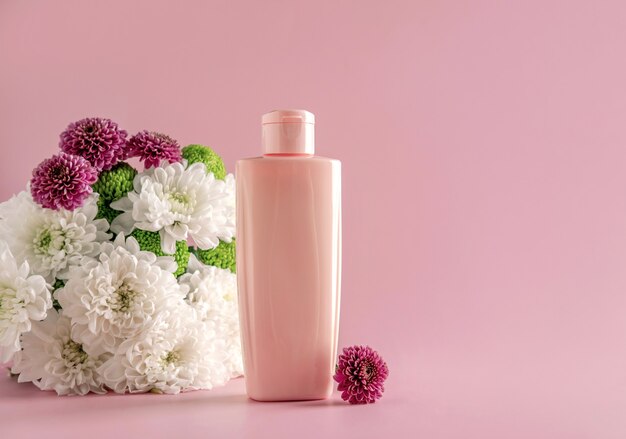 Foto simulacros de cosmética natural: suero, crema, mascarilla para publicidad sobre fondo rosa claro con flores. productos orgánicos. concepto de spa