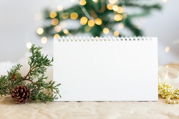 Simulacros de espacio de copia Calendario espiral en blanco con bokeh dorado brillante sobre fondo de árbol nuevo