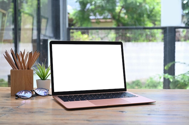 Simulacros de gafas de planta de computadora portátil y portalápices en la mesa de madera