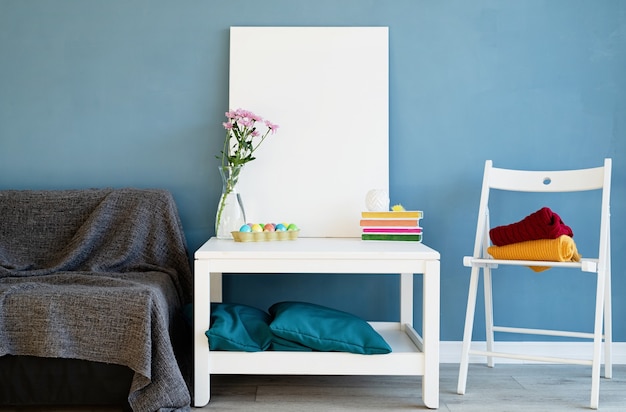 Simulacros de marco de póster blanco en la mesa de café en la habitación azul. Lienzo blanco en blanco en el interior