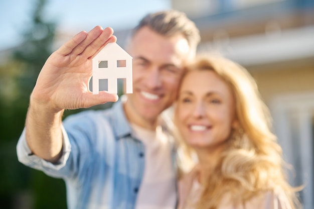 Sinal da casa na mão do homem abraçando a esposa