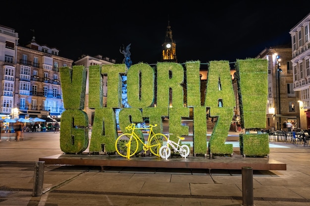 Foto sinal da cidade de vitória iluminada à noite na plaza de la virgen blanca espanha