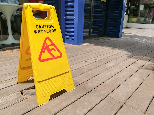 Foto sinal de aviso de piso molhado de precaução com turva no chão de madeira.