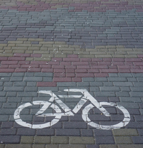 Sinal de bicicleta pintado com tinta branca em um pavimento de mosaico de pedra