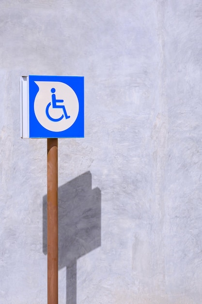 Sinal de cadeira de rodas com deficiência de estacionamento na parede de concreto do loft fora do prédio em quadro vertical