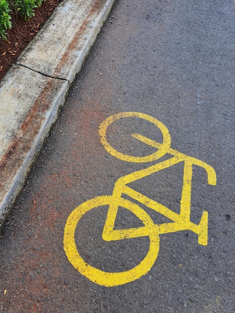 Sinal de ciclovia em amarelo com linhas sólidas na estrada de asfalto na Indonésia