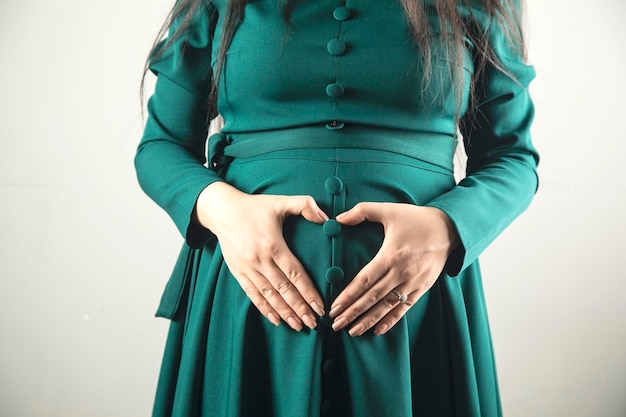 Sinal de coração de mão de mulher grávida na barriga