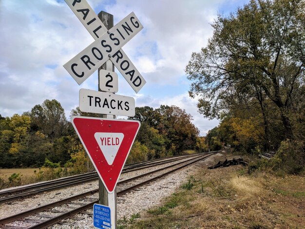 Foto sinal de estrada por trilhas ferroviárias contra o céu