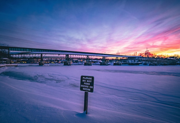 Sinal de informação sobre neve contra o céu durante o pôr-do-sol