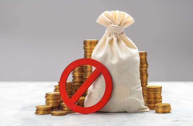 Sinal de proibição Saco de dinheiro e pilhas de moedas em um fundo cinza Sem símbolo e dinheiro