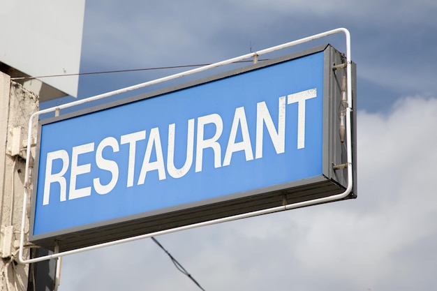 Foto sinal de restaurante vintage na construção de texto básico simples de fachada em luz de fundo azul