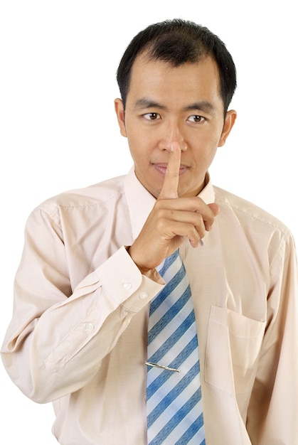 Sinal de silêncio com o dedo do empresário asiático perto dos lábios em fundo branco.