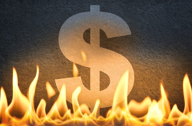Foto sinal do símbolo da moeda do dólar americano queimando em chamas de fogo, como símbolo da crise da economia americana, declínio e queda ou interrupção do mercado dos eua