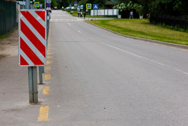 Sinal listrado diagonal vermelho e branco na extremidade da cerca da estrada