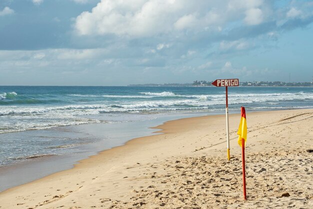 Sinal na areia da praia indicando perigo escrito em língua portuguesa