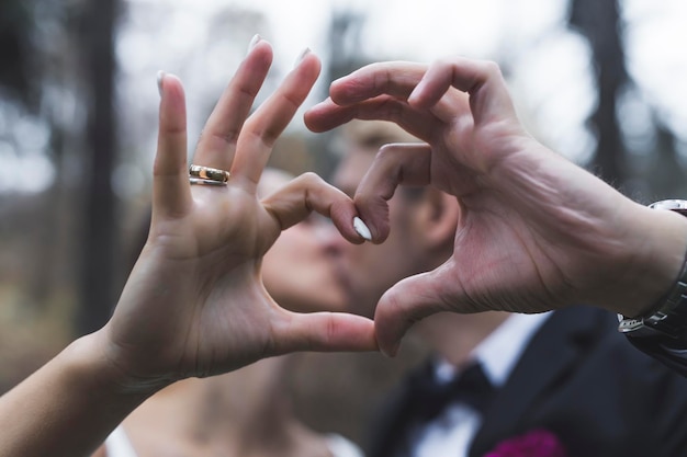 Sinal simbólico do coração feito por um casal heterossexual recém-casado Sessão de fotos ao ar livre recém-casados Beijo turvo Esposa turca e marido escandinavo