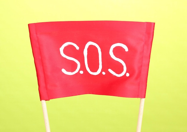 Sinal SOS escrito em pano vermelho sobre fundo verde