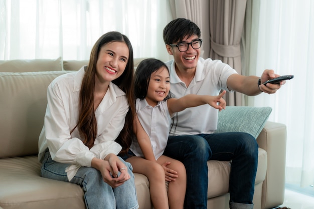 Sincero de la feliz familia asiática disfruta de la actividad de fin de semana viendo programas de televisión en casa.