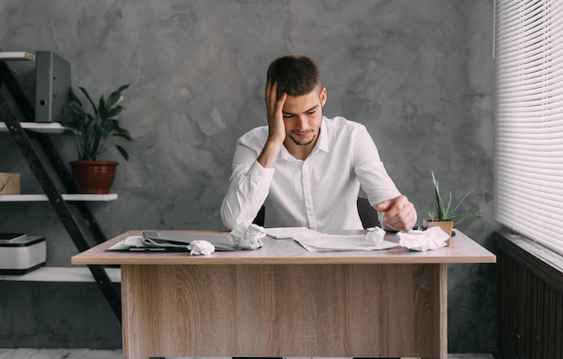 Síndrome de burnout en el trabajo Joven empresario estresado en el lugar de trabajo con dolor de cabeza trabajos desmotivados con papeles Migraña en jóvenes Concepto de trabajo y fatiga