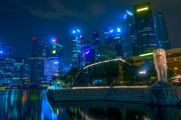 Singapur de noche. Centro con rascacielos y Merlion