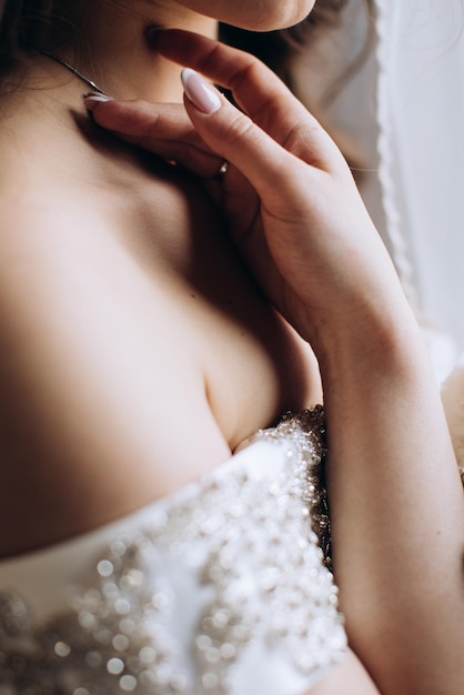 Sinnliche Braut im weißen Kleid berührt ihr Gesicht mit der Hand