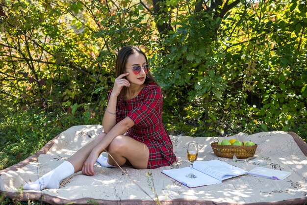 Sinnliche junge Frau im roten Kleid ruht in der Natur, die in der Sommerzeit der Decke liegt