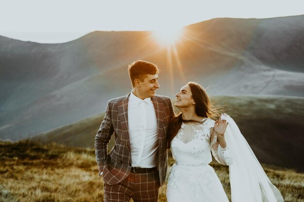 Sinnliches Hochzeitspaar, Bräutigam und Braut in einem langen weißen Kleid, das am Rande der Berge steht