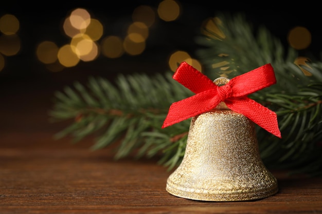 Foto sino com arco vermelho e ramos de abeto em mesa de madeira contra fundo desfocado decoração de natal