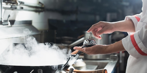 Sino de serviço. Chef de mãos segurando um sino para o conceito de cozinha de restaurante aberto