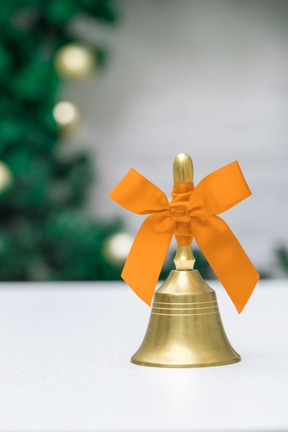 Sino dourado com fita laranja no fundo branco e véspera de ano novo na árvore de Natal