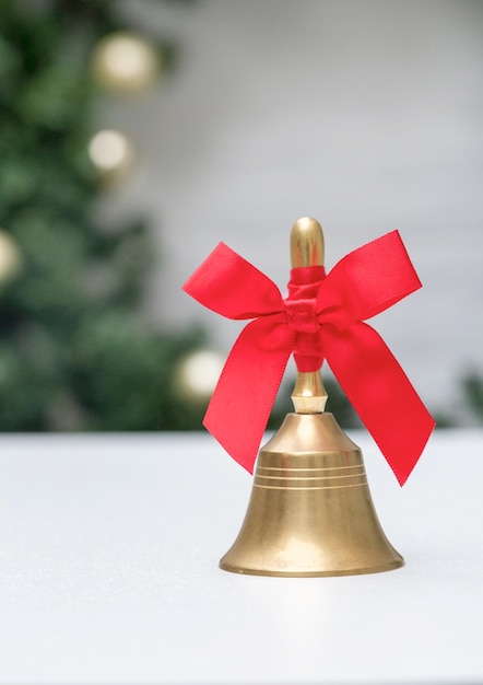 Sino dourado com fita vermelha no fundo branco e véspera de ano novo na árvore de natal