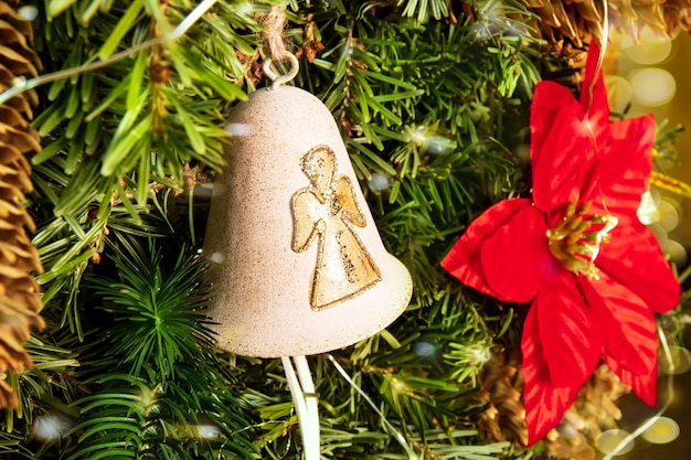 Sino dourado com um anjo de Natal em uma árvore tradicionalmente decorada com uma estrela de Natal e bokeh