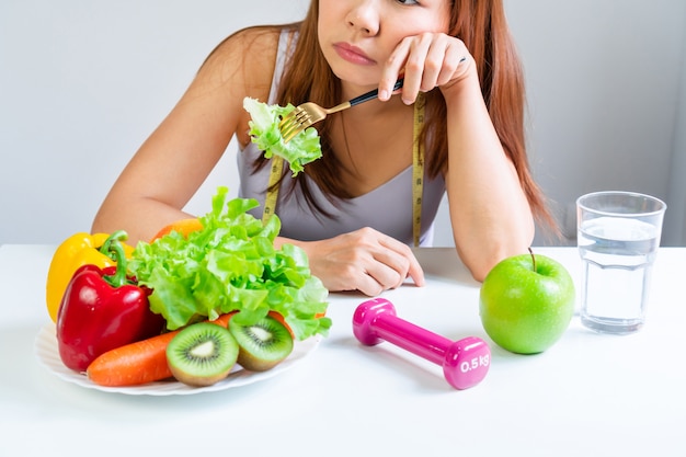 Los síntomas de la anorexia se manifiestan en la aversión a la comida. Retrato de joven asiática en expresión emocional facial insatisfecha, negándose a comer verduras y frutas. De cerca