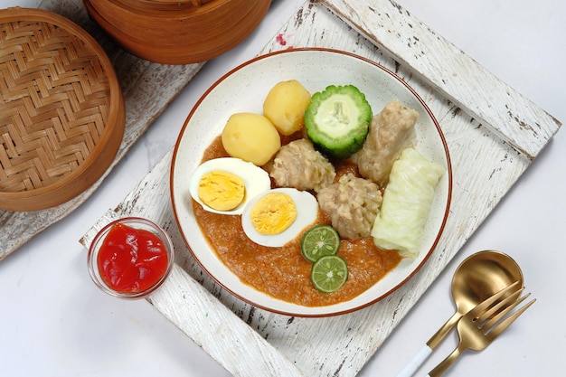 Siomay oder Somai, indonesischer gedünsteter Fischknödel mit Gemüse, serviert in Erdnusssoße.