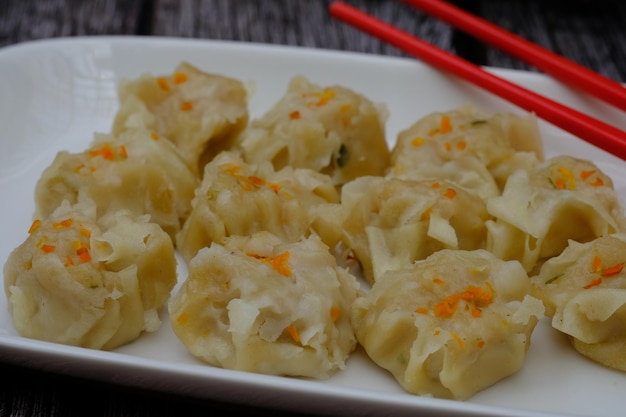 siomay en un plato de cerámica blanca. salsa de tomate. salsa de chile suma tenue shumai comida japonesa, china.